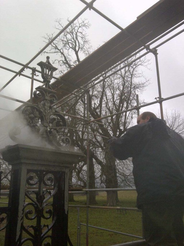 Conservation Blacksmith, carefully pressure washing. Pressure washing of the 'Tijou' gate to remove loose layers (this operation was done before the protective enclosure was erected for obvious reasons.