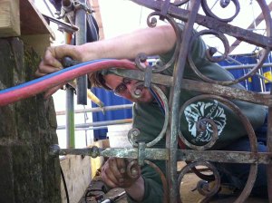 Conservation Blacksmith cleaning difficult to reach parts using an adapted blade.